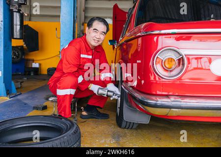 Senior professionelle asiatische männliche Mechaniker Garagenarbeiter glücklich arbeitende Reifen Räder ersetzen Auto Reifen Wartung Service Stockfoto