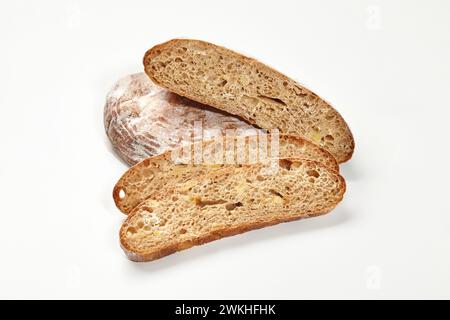 Ganze und in Scheiben geschnittene Laibe von Weizenbrot mit knuspriger bräunlicher Kruste und luftiger Textur auf weißem Hintergrund. Bäckerei- und Brotbackkonzept Stockfoto