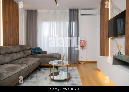 Modernes, stilvolles und gemütliches Wohnzimmer mit braunem Sofa und rundem Couchtisch Stockfoto