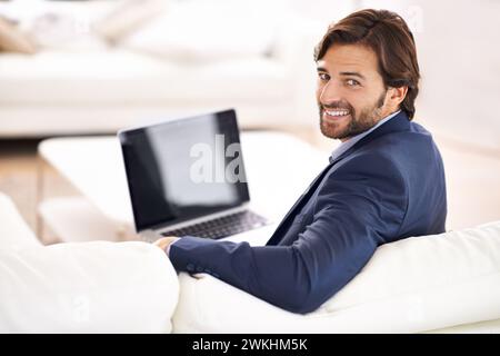 Geschäftsleute, Mann und Lächeln im Wohnzimmer mit Laptop auf der Couch, Fernarbeit und kleine Unternehmen mit Vertrauen in Anzug. Sofa, Lounge und professionell Stockfoto