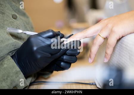 Maniküre, die die Nägel entfernt, poliert. Professionelle Maniküre-Behandlung im Schönheitssalon. Handhygiene und Pflege in der Schönheitsindustrie. Stockfoto