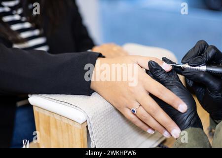 Maniküre, die die Nägel entfernt, poliert. Professionelle Maniküre-Behandlung im Schönheitssalon. Handhygiene und Pflege in der Schönheitsindustrie. Stockfoto