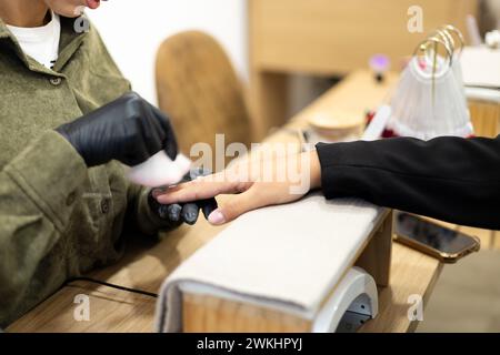 Maniküre, die die Nägel entfernt, poliert. Professionelle Maniküre-Behandlung im Schönheitssalon. Handhygiene und Pflege in der Schönheitsindustrie. Stockfoto