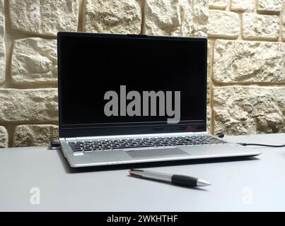 Ein offener Laptop und Stift auf einem Tisch in der Nähe von Felsen Stockfoto