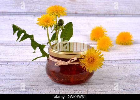Löwenzahnmarmelade in den Gläsern auf einem Holztisch, mit frischen Blumen. Nahaufnahme. Stockfoto