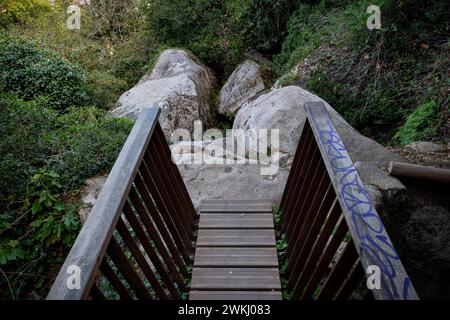 Die Fußgängerbrücke endet zu einer kleinen Lichtmauer mit Felsbrocken im Wald des Sintra-Gebirges in Portugal. Stockfoto