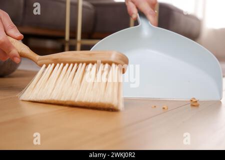 Nahaufnahme von Frauenhänden, die die Wohnung mit kleinem Besen und Kehrschaufel reinigen Stockfoto