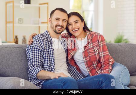 Porträt eines verliebten kaukasischen Paares, das lächelnd und umarmt auf dem Sofa sitzt. Stockfoto