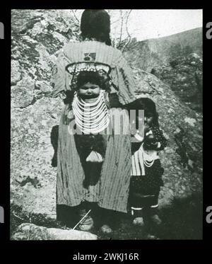Pacific Northwest Indigenous People Um 1900, Foto,. Warm Springs Matron mit ihren Papoosen. Mit ausgeklügeltem Babybrett. Diese Babybretter werden auf dem Rücken der indischen Frauen getragen. Wir könnten hier erwähnen, dass die Frauen es sehr vorziehen, als indische Frauen zu „Squaw“ bezeichnet zu werden) und wenn sie gemischtblütig sind, werden Sie sich bei ihnen viel beliebter finden, wenn Sie daran denken, „gemischtes Blut“ anstatt „Rasse“ zu sagen. Wir alle sind unsere eigene Spezies des Stolzes. Stockfoto