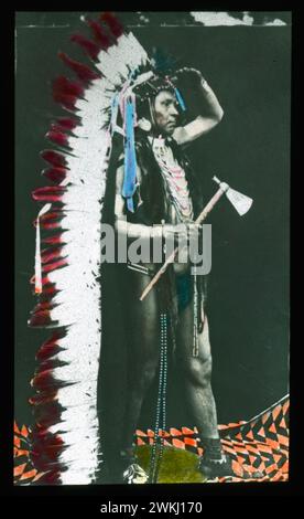 Indigene Im Pazifischen Nordwesten Um 1900, Foto, Handkoloriert. Porträt eines der Hauptmänner der Columbia River Indians, Porträt in voller Kleidung mit Federkopfbekleidung und Tomahawk Stockfoto