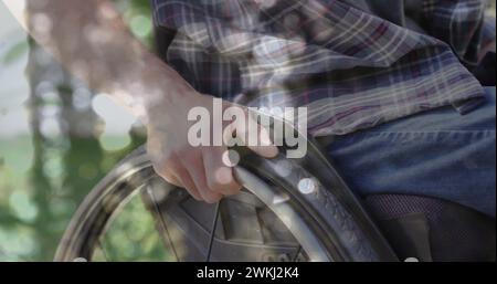 Bild von Lichtflecken über behindertem kaukasier, der im Rollstuhl sitzt Stockfoto