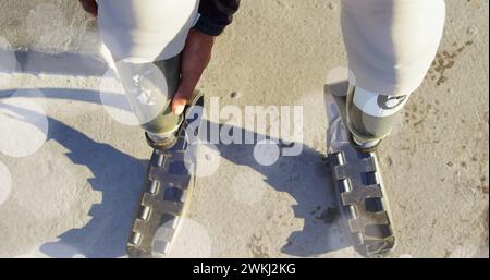 Bild von Lichtflecken über behinderten afroamerikanischen Frauen mit künstlichen Beinen Stockfoto