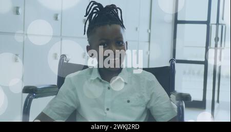 Bild von Lichtflecken über behinderten afroamerikanischen Jungen, der im Rollstuhl sitzt Stockfoto