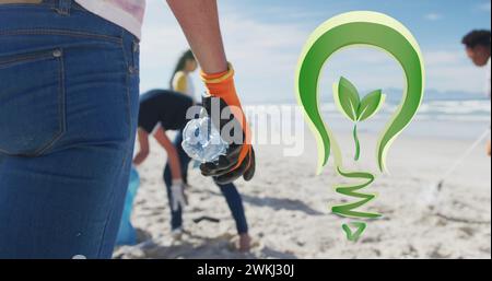 Bild: Go Green Glühlampe Logo über verschiedenen Gruppen, die Müll vom Strand aufsammeln Stockfoto