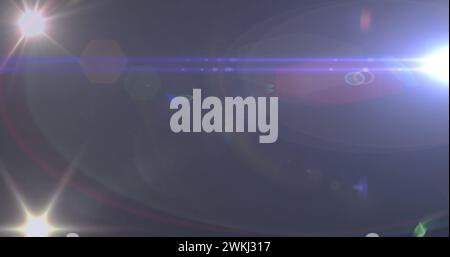 Bild eines Scheinwerfers mit Streulicht und Lichtstrahlen, die sich über einen dunklen Hintergrund bewegen Stockfoto