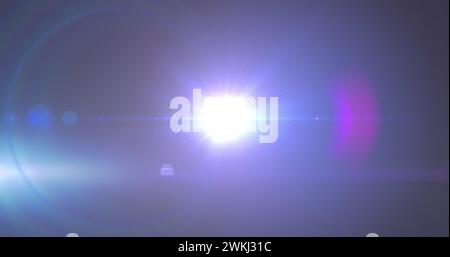 Bild eines Scheinwerfers mit Streulicht und Lichtstrahlen, die sich über einen dunklen Hintergrund bewegen Stockfoto