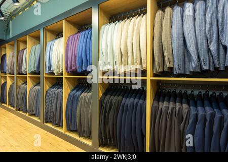 Eine Reihe von Männeranzügen, Jacken, die auf einem Regal hängen, um sie auszustellen. Elegante Herrenanzüge hängen in einer Reihe an Kleiderbügeln. Stockfoto