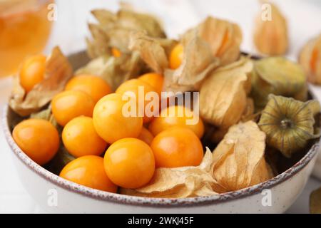 Reife Physalis-Früchte mit Kelchen in der Schüssel auf dem Tisch, Nahaufnahme Stockfoto