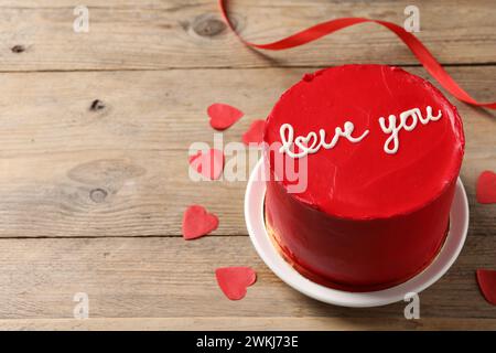Bento Kuchen mit Text Love You und Papierherzen auf Holztisch, Platz für Text. St. Valentinstag-Überraschung Stockfoto