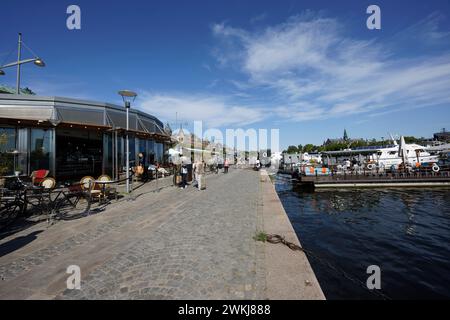 Auf der historischen Strandvagen-Uferpromenade spazieren die Menschen an Cafés, Bars und Booten im Ladugårdslandsviken-See, Ostermalm, Stockholm Stockfoto