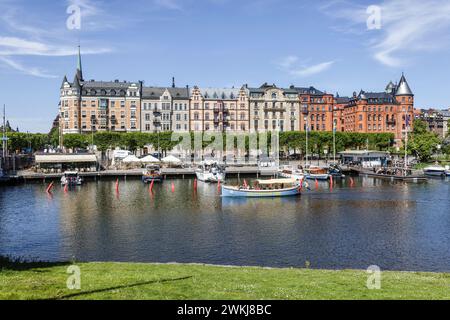 Boote, die an der Strandvägen-Kai-Promenade auf dem historischen, baumbestandenen Boulevard vor Anker liegen, an Gebäuden in Bajonetten-Gegend in Ostermalm, Stockholm. Stockfoto