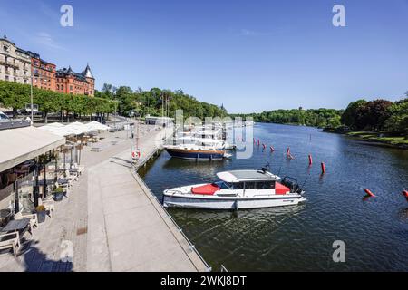 Boote, die an der Strandvägen-Kai-Promenade auf dem historischen, baumbestandenen Boulevard vor Anker liegen, an Gebäuden in Bajonetten-Gegend in Ostermalm, Stockholm. Stockfoto