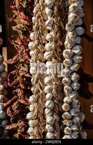 Knoblauchschnur mit getrocknetem Räucherfleisch, sonnengetrocknetem Paprika und Kräutern und frischem Gemüse in der Speisekammer Stockfoto