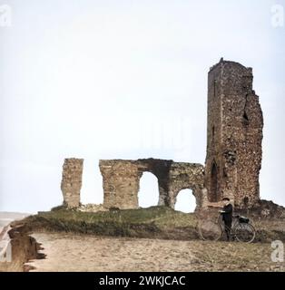 Farbige Zauberlaterne Rutsche des Jungen mit Fahrrad, stehend an Ruinen der All Saints Church, Dunwich, Suffolk, England, um 1900 Stockfoto