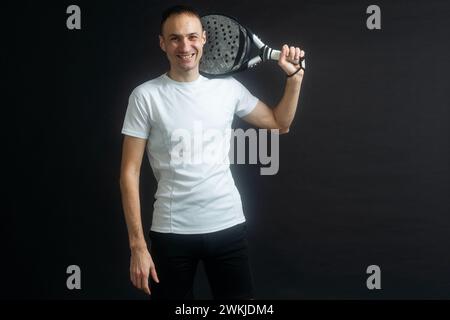 Porträt eines Mannes, der Paddeltennis spielt, in Position, um einen schwarzen, isolierten Hintergrund zu treffen. Vorderansicht. Stockfoto