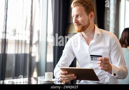 Glücklicher erfolgreicher Geschäftsmann beim Online-Shopping oder zufriedener Unternehmer bei Online-Zahlungen Stockfoto
