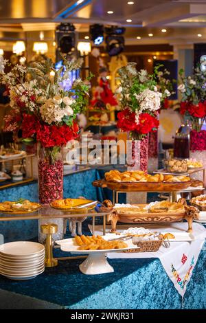 Ein wunderschön dekorierter Tisch ist voll mit einer Auswahl an leckeren Backwaren, Brot und Blumenmustern. Stockfoto