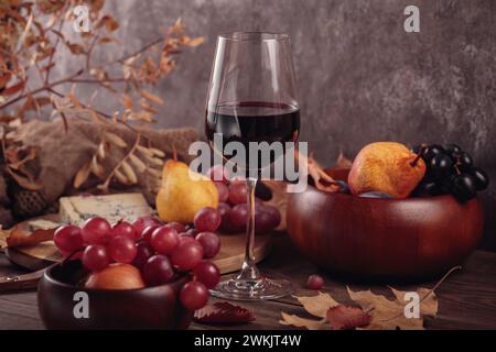 Herbstpicknick mit Wein- und Käseplatte, Früchten und trockenen Blättern Stockfoto