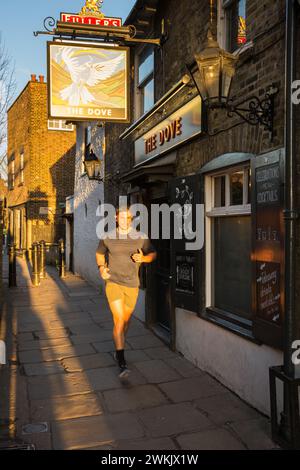 Ein junger Mann joggt vor dem Dove Public House in Hammersmith, West London, England, Großbritannien Stockfoto