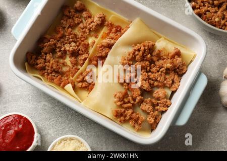 Lasagne kochen. Nudellaken und Hackfleisch in Backblech auf einem hellen, strukturierten Tisch, flach gelegt Stockfoto