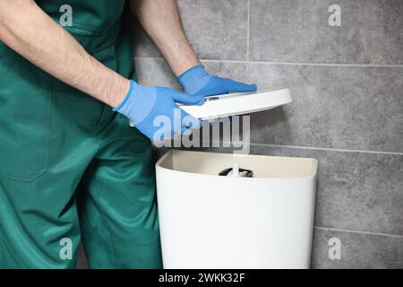 Der Klempner repariert die Toilettenschüssel im Wasserschrank, Nahaufnahme Stockfoto