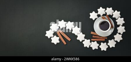 Weiße Tasse und Untertasse Espresso-Kaffee auf einem Hintergrund aus verstreuten glasierten Lebkuchen, Zimtstangen und Gewürzen. Duftender Snack. Flache Lage, oben VI Stockfoto