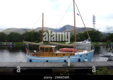 Vergnügungsboot, das auf dem Tow Path auf dem Caledonian Canal mit Ben Nevis an der „Neptunes-Treppe“ in der Nähe von Fort William in den Highlands von Schottland verankert ist. Stockfoto