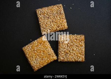 Bis Chikki auf schwarzgrauem Hintergrund. Till Chikki ist ein indisches Süßwarengericht, das mit Jaggery und Sesam zubereitet wird. Indisches Festival makar sankranti besonderes Süßes Stockfoto