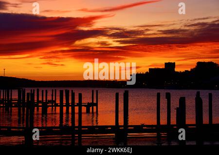 Ruhiger Sonnenuntergang am Ufer mit Silhouetten-Pier Stockfoto