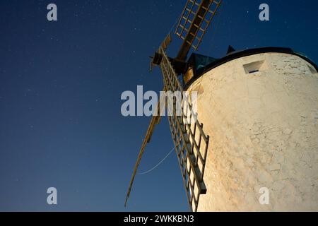 Windmühle im Vordergrund mit großen Holzklingen unter einem sternenklaren Nachthimmel im Hintergrund. Consuegra. Spanien. Stockfoto