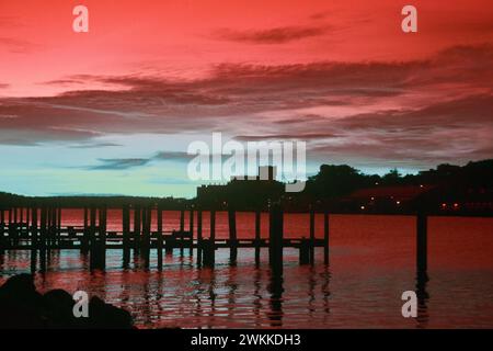 Ruhige Sonnenuntergang Reflexionen auf dem See mit Pier und Fernschloss in Infrarot Stockfoto