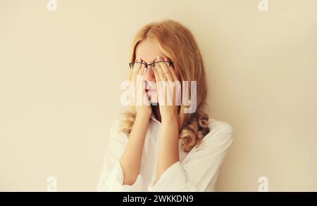 Müde überarbeitete junge Angestellte, die sich nach der Arbeit am Computer die Augen reibt und unter Augenschmerzen oder Kopfschmerzen leidet. Erschöpfter Büroangestellter Stockfoto