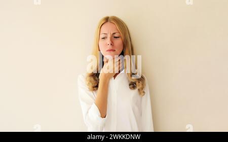 Kranke erschöpfte junge Frau berührt ihren Hals mit der Hand, während sie an akuten Schmerzen in der Rachengrippe leidet, fühlt sie sich schlecht Stockfoto