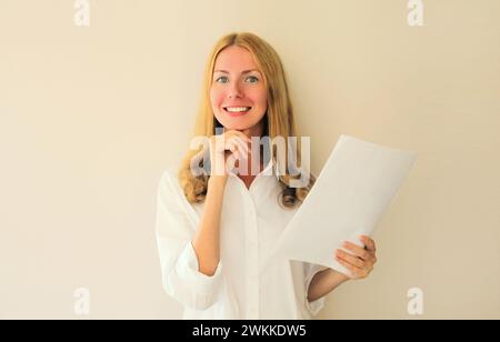 Porträt einer glücklichen, lächelnden kaukasierin mit weißem, leerem Blatt Papier, das im Büro in die Kamera blickt Stockfoto