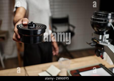 Abgeschnittener afroamerikanischer Fotograf, der Filmkanisterdeckel in Dunkelkammer sichert, analoge Entwicklung Stockfoto