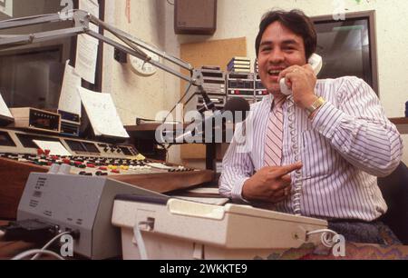 San Antonio Texas USA, 1991: Man spricht am Telefon, während er eine Sendung aus dem Kontrollraum des spanischsprachigen Radiosenders KCOR ausstrahlt. ©Bob Daemmrich Stockfoto