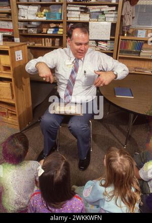 Austin Texas USA, 1992: Ein anglo Geschäftsmann mittleren Alters dient als Geschichtenerzähler für Kindergartenschüler während der Geschichtenzeit in ihrem Klassenzimmer. ©Bob Daemmrich Stockfoto