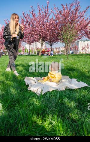 Mutter und Kind genießen die Kirschblütensaison mit Seifenblasen. Stockfoto