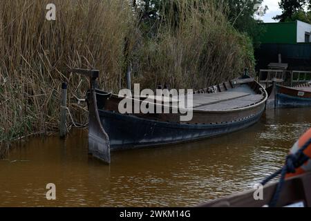 Ein teilweise untergetauchtes und vergessenes Boot an einem verwitterten Dock spiegelt eine Geschichte der Vernachlässigung in den Gewässern von Albufera Valencia wider Stockfoto