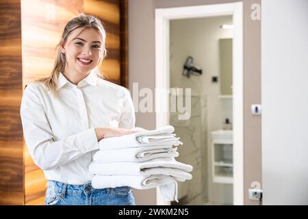 Porträt eines lächelnden Zimmermädchens mit frischen Handtüchern im Hotelzimmer. Stockfoto